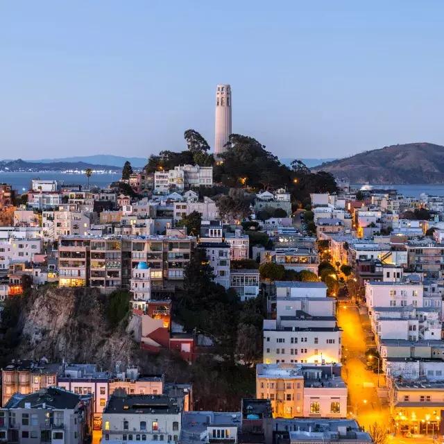 贝博体彩app的科伊特塔在黄昏, con calles iluminadas delante y la Bahía de San Francisco detrás.